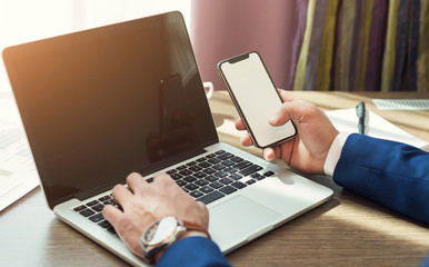 Businessman holding empty smartphone and laptop