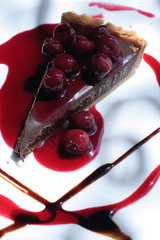 Chocolate piece of cake on white plate with cherries