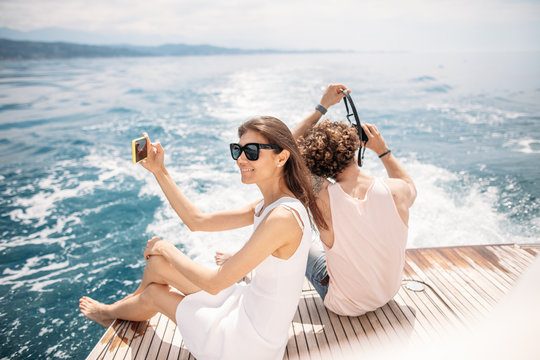 Rear view of a caucasian couple on boat feed, shooting video of beautiful sea view on their cell telephones with blank copy space for advertising text message during boating in yacht