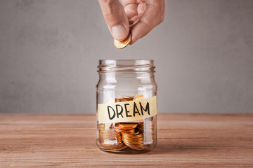Dream. Glass jar with coins and an inscription dream. Man holds  coin in his hand