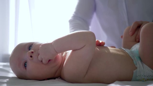 massagist rubs and strokes the tummy of newborn in his office on background of bright window close-up