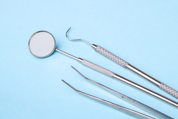 Dental instruments. Dental mirror, probe hook, tweezers on blue