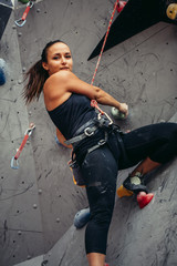Close up of athletic female climber practicing rock climbing on artificial wall indoors. Active lifestyle and Rock climbing concept.