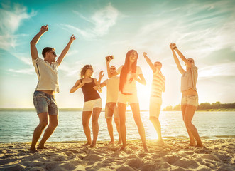 Friends funny dance on the beach under sunset sunlight. Sunny day