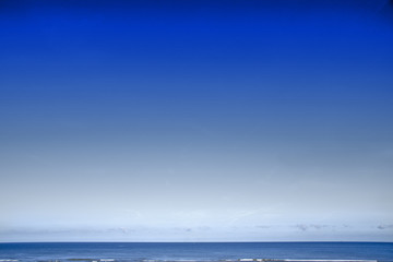 Deep blue color sky gradient background of a seascape with flat horizon and few calm waves