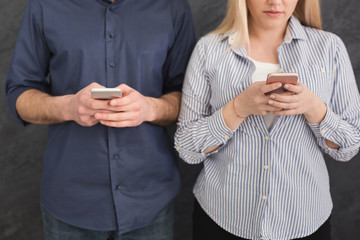 Young unrecognizable couple ignoring each other with phones