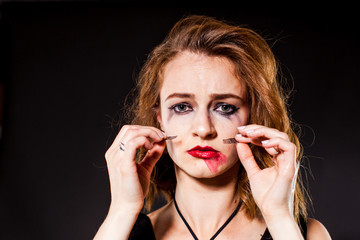 Tearful young woman holds false eyelashes.