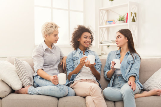 Three female friends with coffee chatting at home