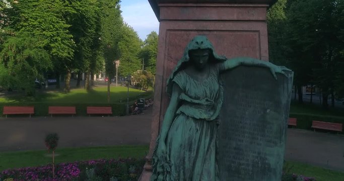 City central park, C4k aerial rising view infront of Runeberg statue, in Helsinki esplanadi park, on a sunny summer morning dawn, in Helsingfors, Uusimaa, Finland