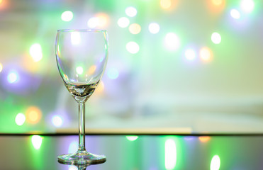 Close up view and copy space. Empty wine glass is on the table and the background is the colorful of sparkling light.