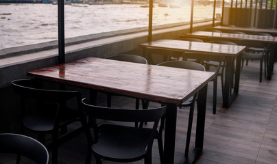 Leading lines view and flare. Empty tables and chairs on the riverside. During the evening with shadows.