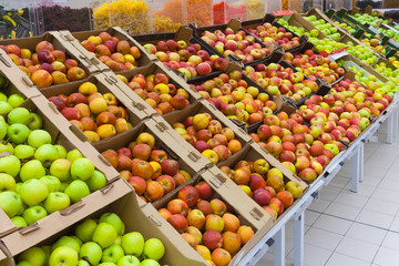 Perspective view of a pile of apples in the cartons boxes on the racks in supermarket
