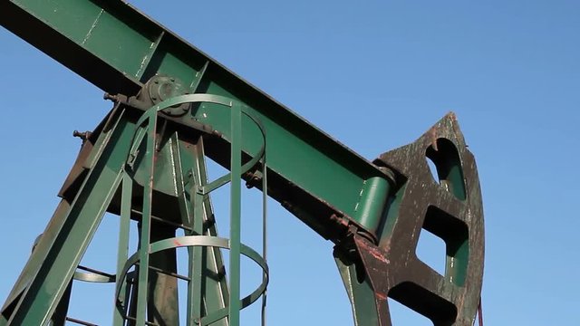  Pump Jack In Action / Crude oil pump jack at an oil extraction site against blue sky. HD1080p