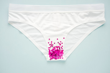 Woman white panties with glitter on pastel baby blue colored background. Menstruation, woman's health, virginity, first sex. Conceptual minimal still life