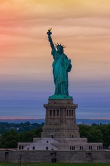 Obraz premium Statue of Liberty with graduated orange and purple sunset in the background