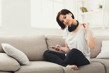 Fototapeta premium Young woman in headphones on beige couch