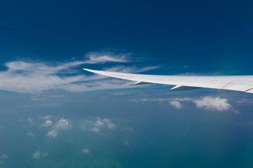 Wing of airplane flying above the clouds in the sky