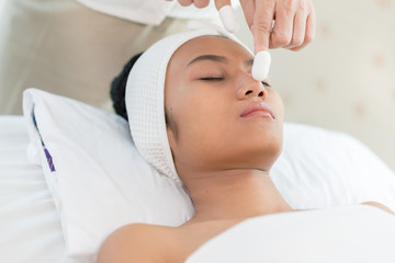 Fototapeta na wymiar Young asian woman enjoying face massage in luxurious beauty salon.