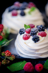 Homemade meringue basis for cake Pavlova with fresh blueberries and BlackBerry and powdered sugar on black  background. Copy space