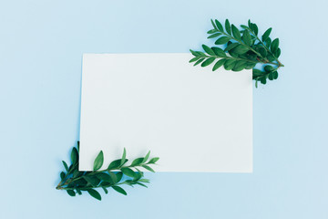 Desktop mock-up with blank paper card, branch on white shabby table background. Empty space. Styled stock photo, web banner. Flat lay
