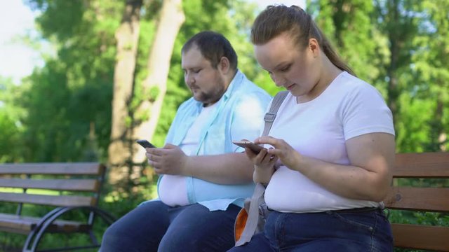 Obese couple posting photos in social network, upset girl waiting for likes