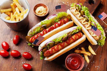 Fast food from hot dog with sausage and fries decorated USA flag on 4th july top view. Table setting on american independence day. - obrazy, fototapety, plakaty