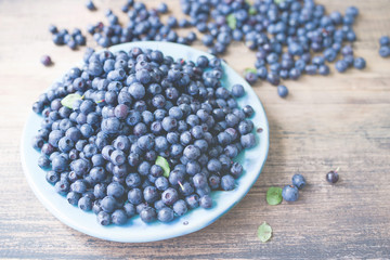 Fresh blueberries on a blue plate on a wooden background closeup