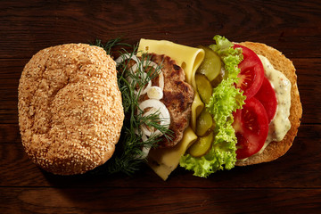Close-up of traditional american burger with lettuce, cheese, onion and tomato on wooden background