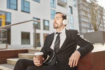 Business Mann mit Kaffeebecher hört Musik