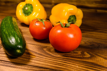 Cucumbers, tomatoes and sweet pepper on wooden table