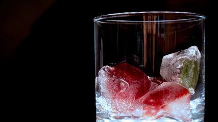 Ice in a transparent glass, black background.