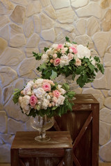 Two flowers bouqet in vases on brown vintage boxes.