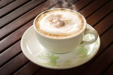 Hot coffee on a wooden table with dark evening. The atmosphere is warm