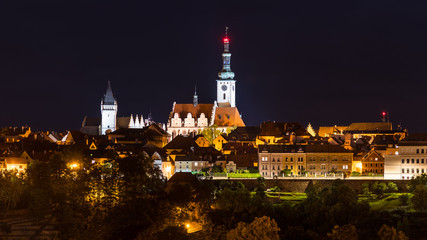 Fototapeta na wymiar Night view on historic Tabor city. Southern Bohemia, Europe. Beautiful evening skyline of illuminated center of the Hussite town with Gothic church tower and dark roofs of old houses.