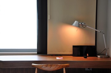 A Working desk with a lamp near windows 