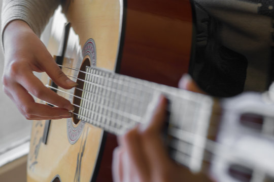 woman's hands playing acoustic guitar, close up