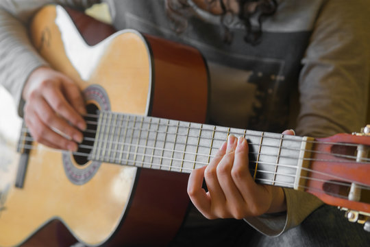 woman's hands playing acoustic guitar, close up