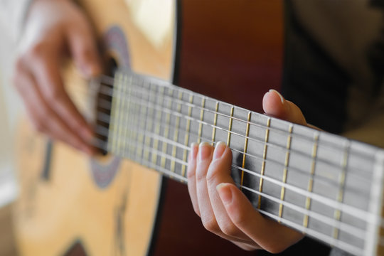 woman's hands playing acoustic guitar, close up