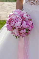 Bride with wedding peony bouquet and pink ribbon.