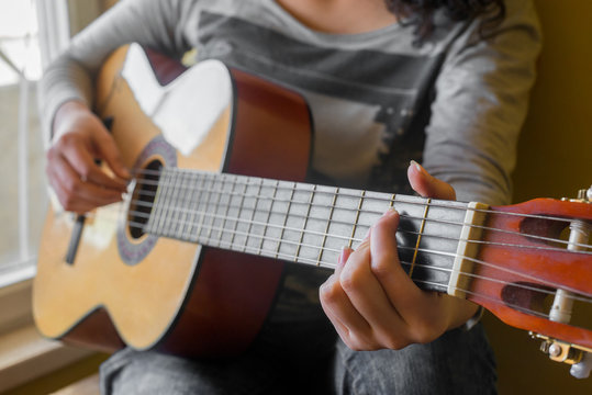 woman's hands playing acoustic guitar, close up
