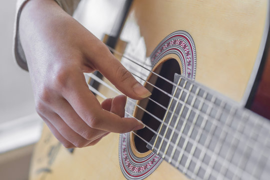 woman's hands playing acoustic guitar, close up