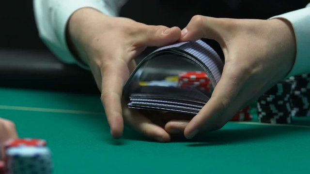 Croupier shuffling and dealing cards, underground casino, illegal gambling