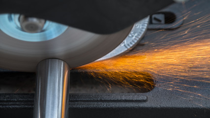 Cutting a metallic rod by a circular saw machine. Close-up of hot sparks when sawing a steel...