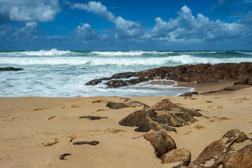 Rocks on the beach. Sky loaded with clouds on a deserted beach. Tropical paradise.