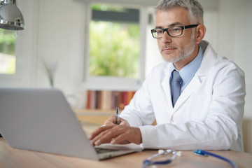 Doctor in office working on laptop computer