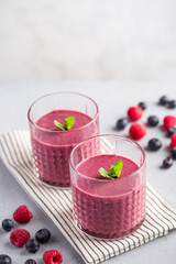 Mixed berry smoothie with mint on light concrete background, copy space