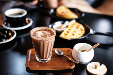 In selective focus of coffee glass on wooden tray,blurry light around