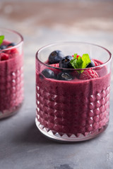 Mixed berry smoothie with mint on concrete background, close up