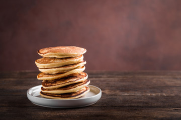 Minimal stack of homemade pancakes on rustic wooden background, copy space