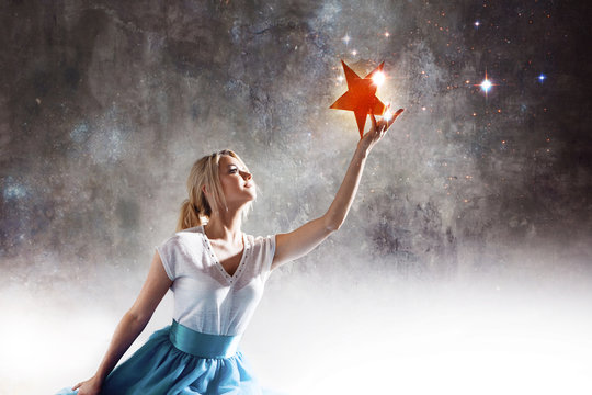 Young attractive woman reaching for the star. Take a star from the sky, dreams and plans, concept